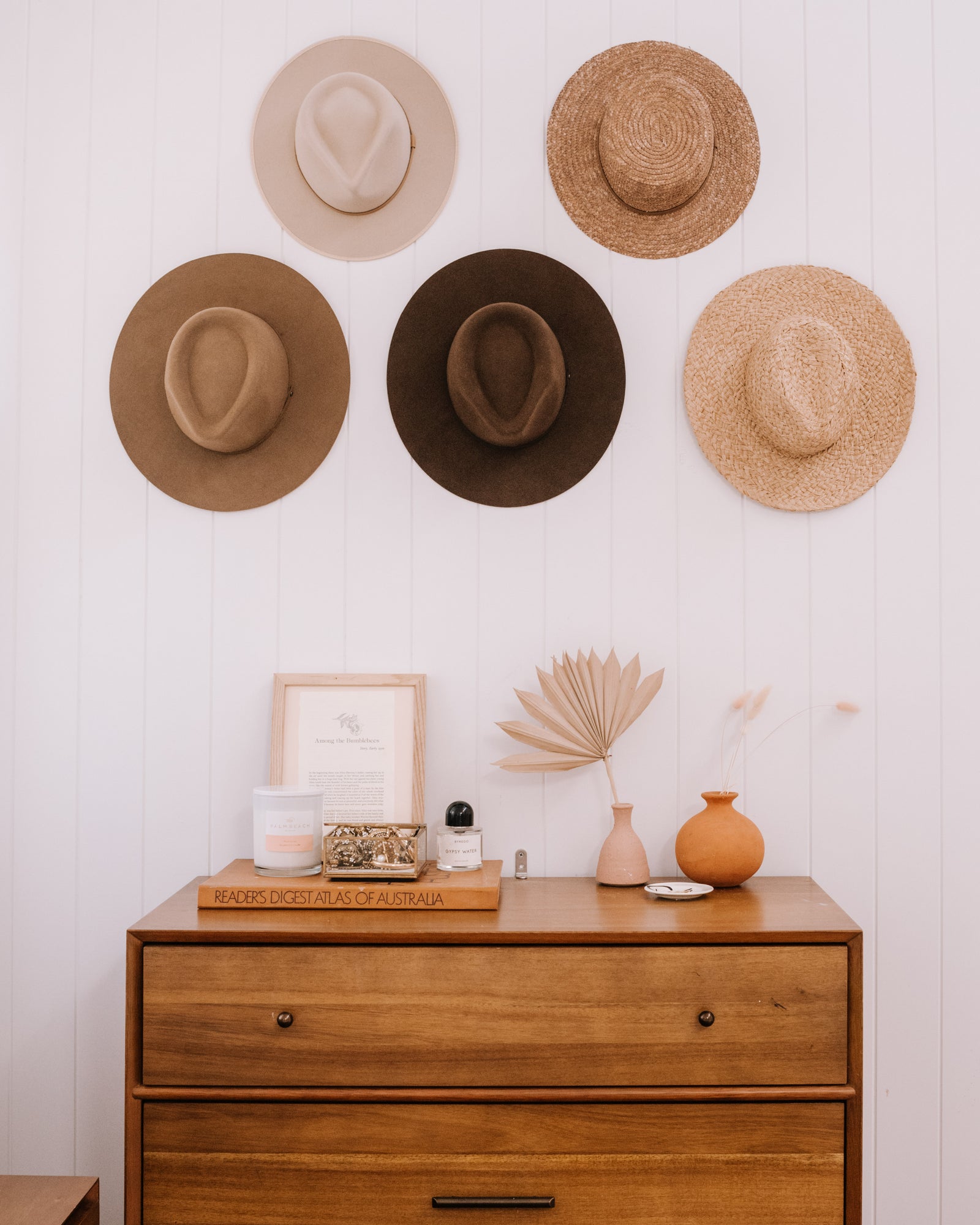 5 wide brim hats hung on a wall with hooks