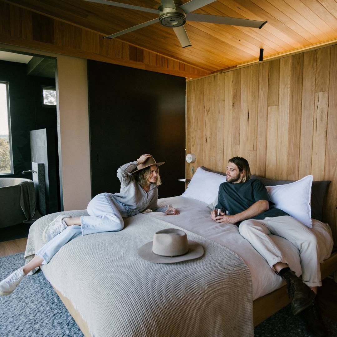 Rachel and her partner lying on the bed inside their cabin stay