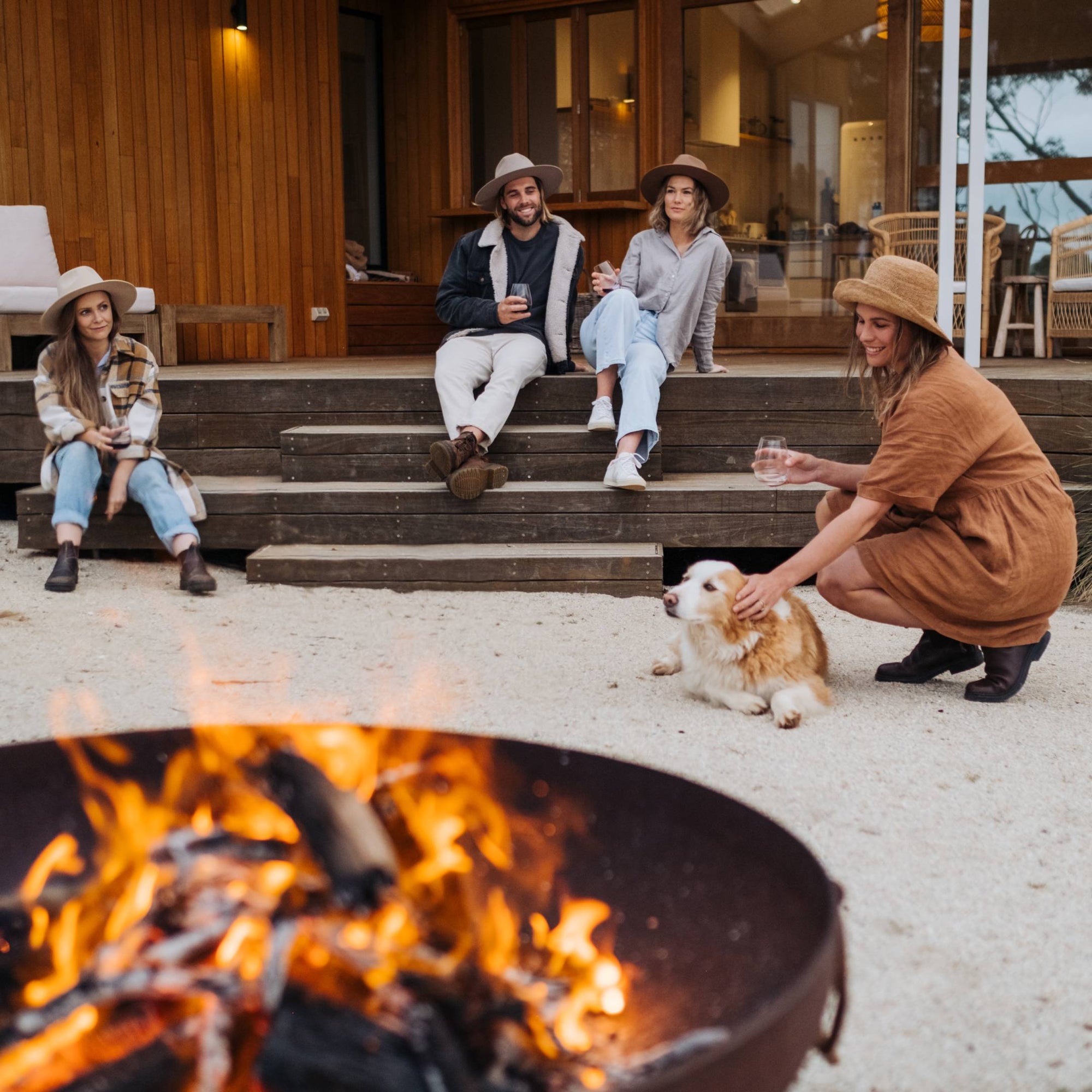 Rachel sits with 3 other people near the fire-pit in the backyard of the cabin they are staying in