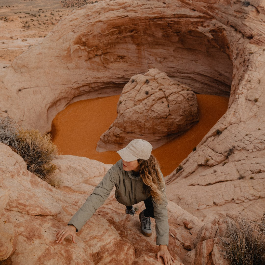 A woman wearing a cap exploring rock formations in the Utah desert