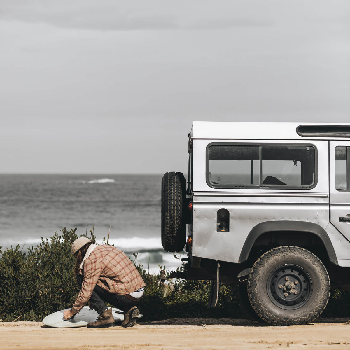 Alex setting up his surfboard fin behind his car ready to go for a surf