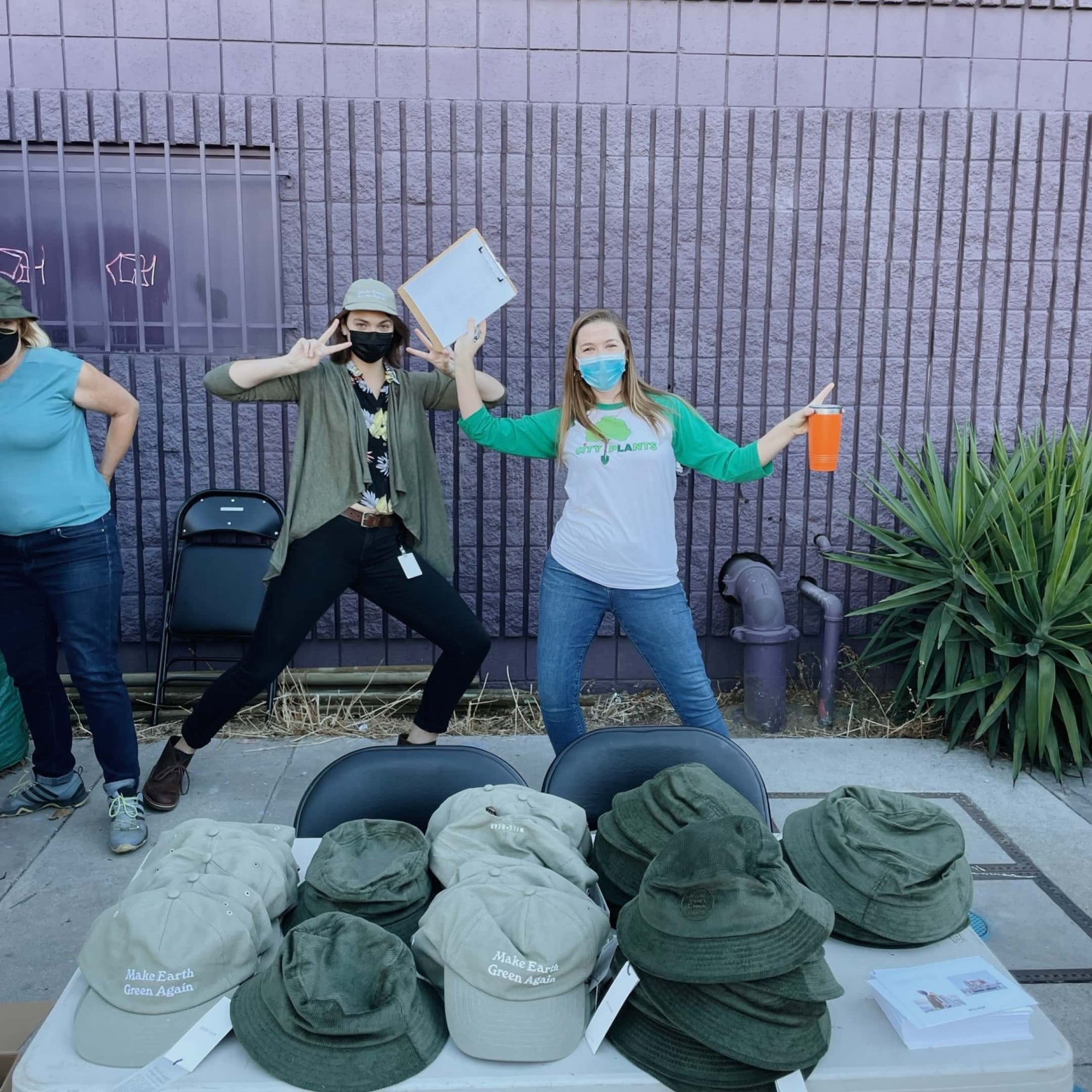 Two people are posing behind a table full of hats and bucket hats