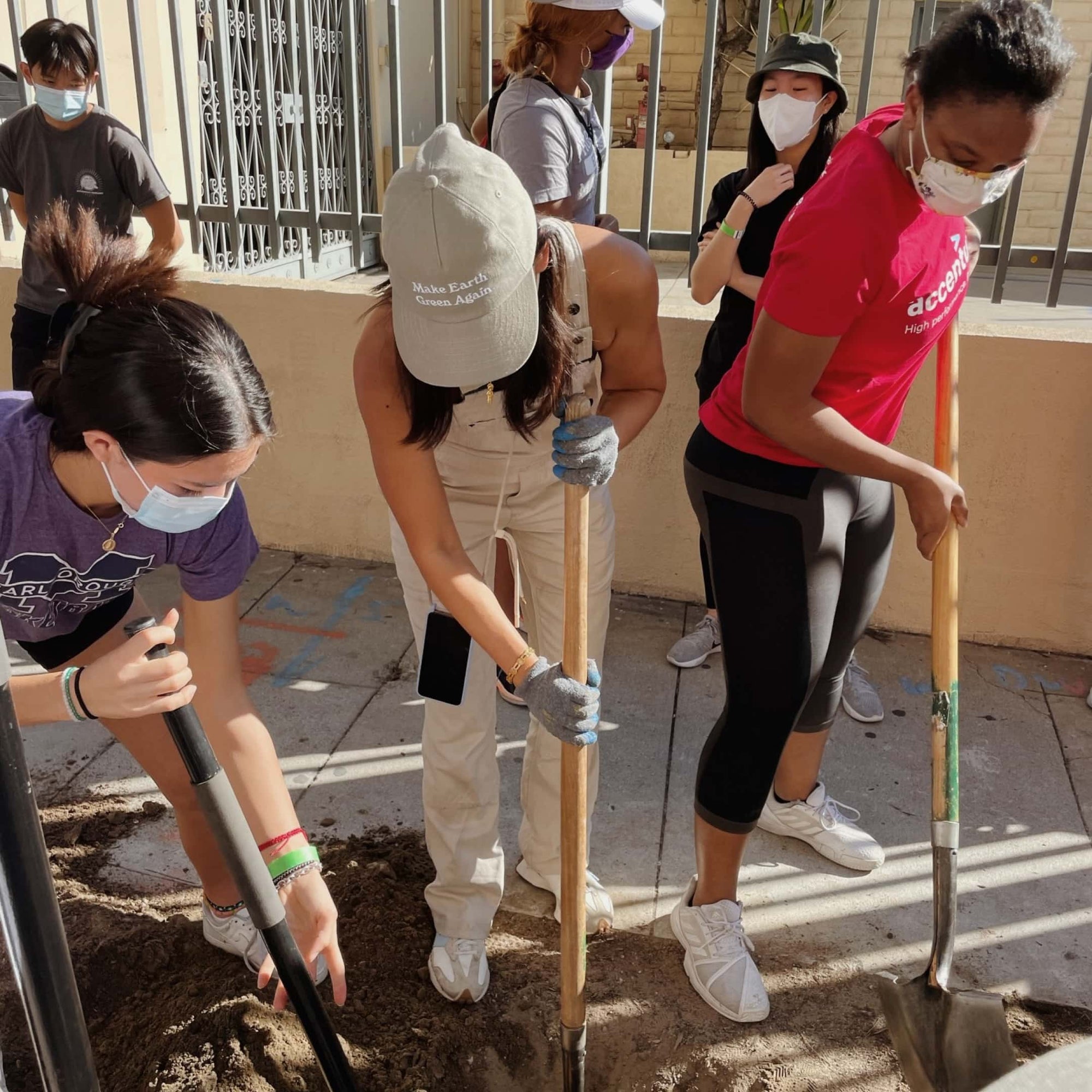 A group of people are digging a hole next to a sidewalk in LA