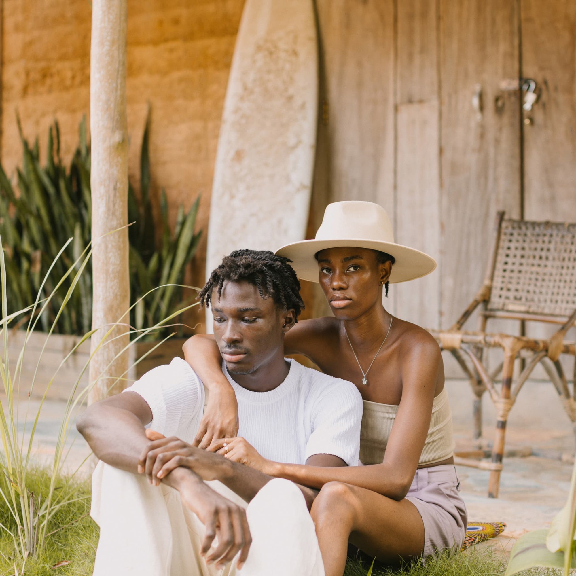 Two people sitting down on the grass in front of a wooden building