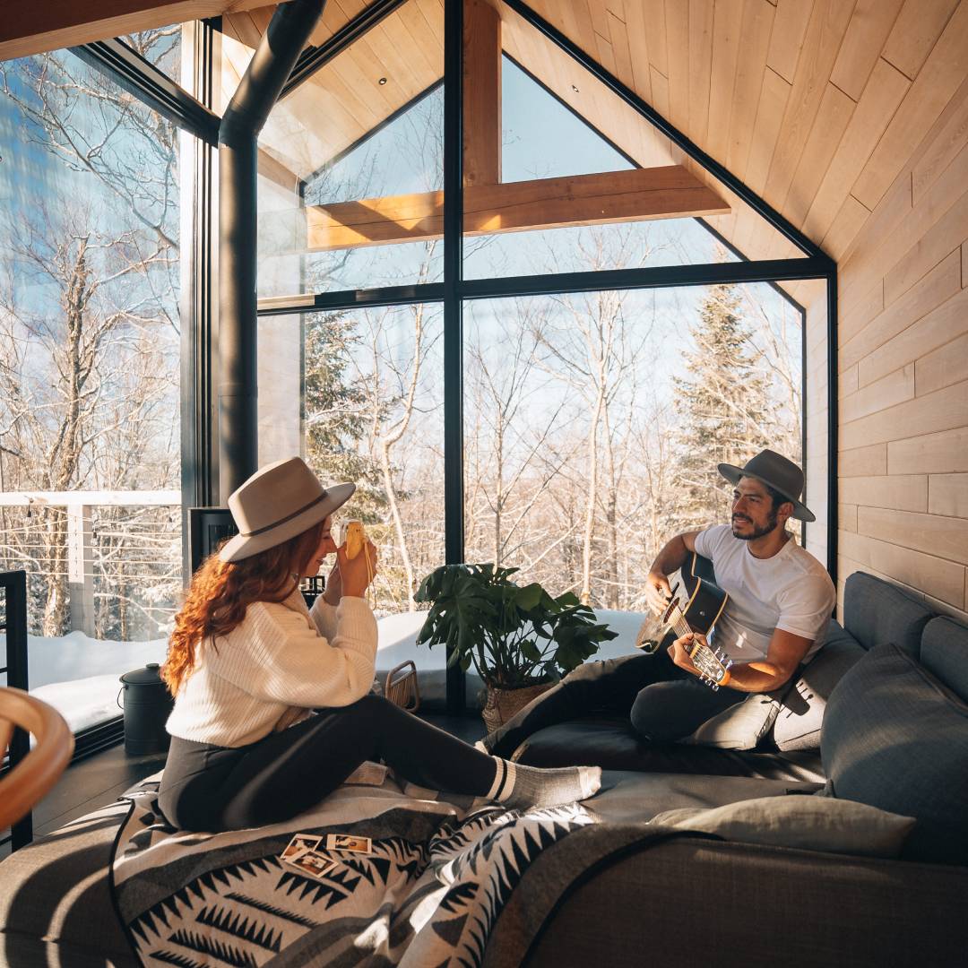 Jenna takes a polaroid photo of her partner playing guitar while sitting in the lounge of The Hygge cabin