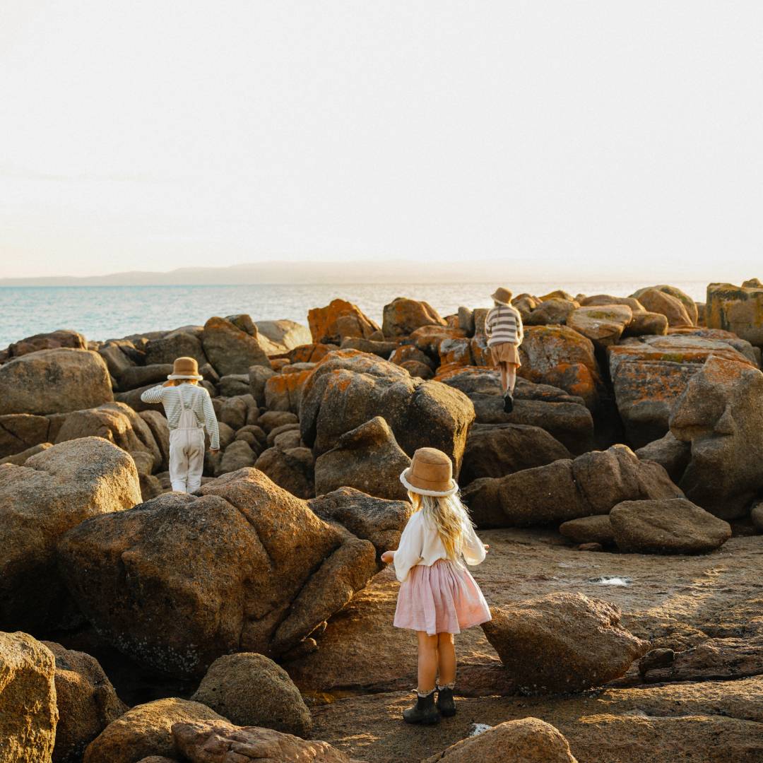 Children exploring rock pools wearing ugg bucket hats