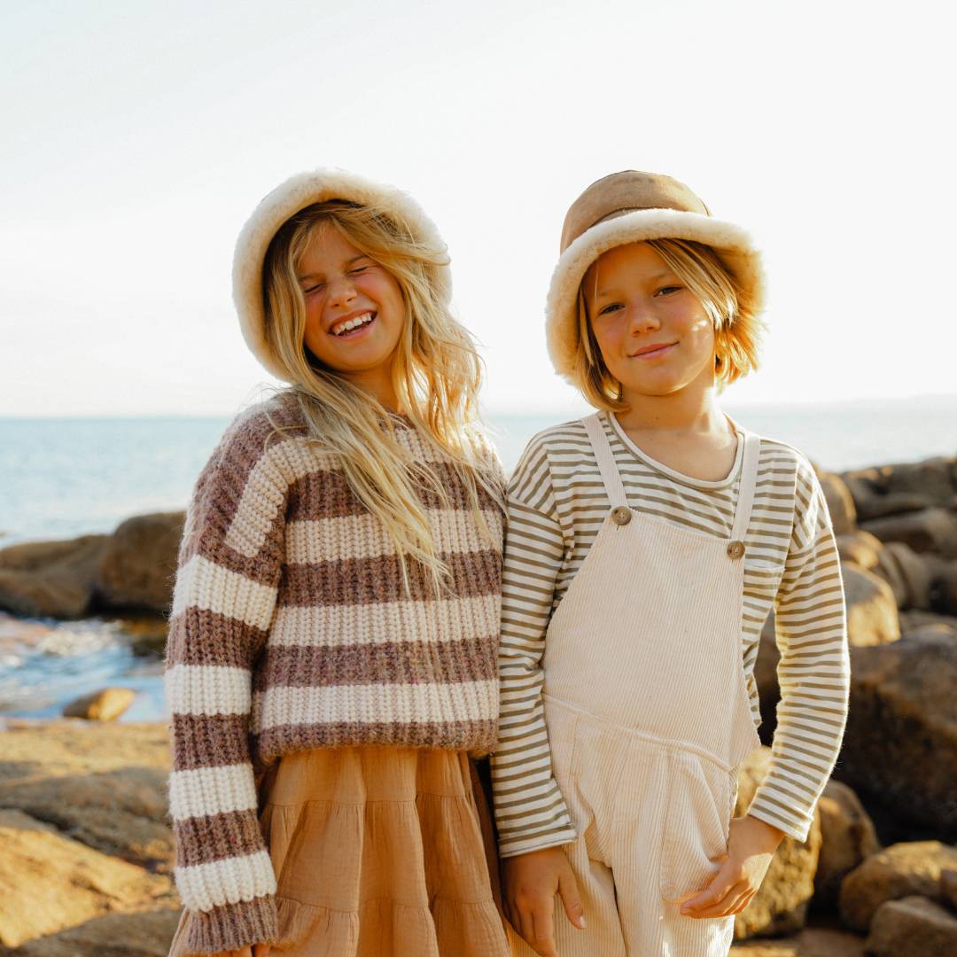 Two children wearing ugg bucket hats standing on some rock pools