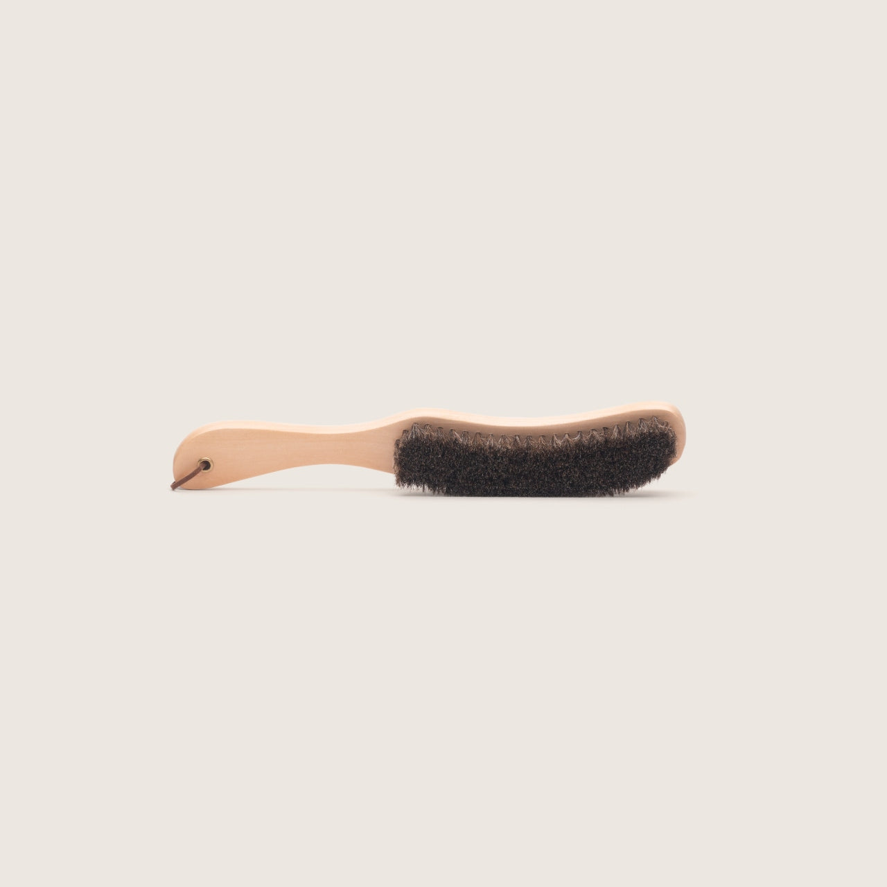Soft bristle hat cleaning brush on a plain beige background