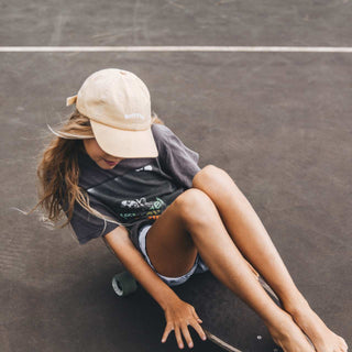 Girl sitting down riding skateboard wearing Little Riley Bone