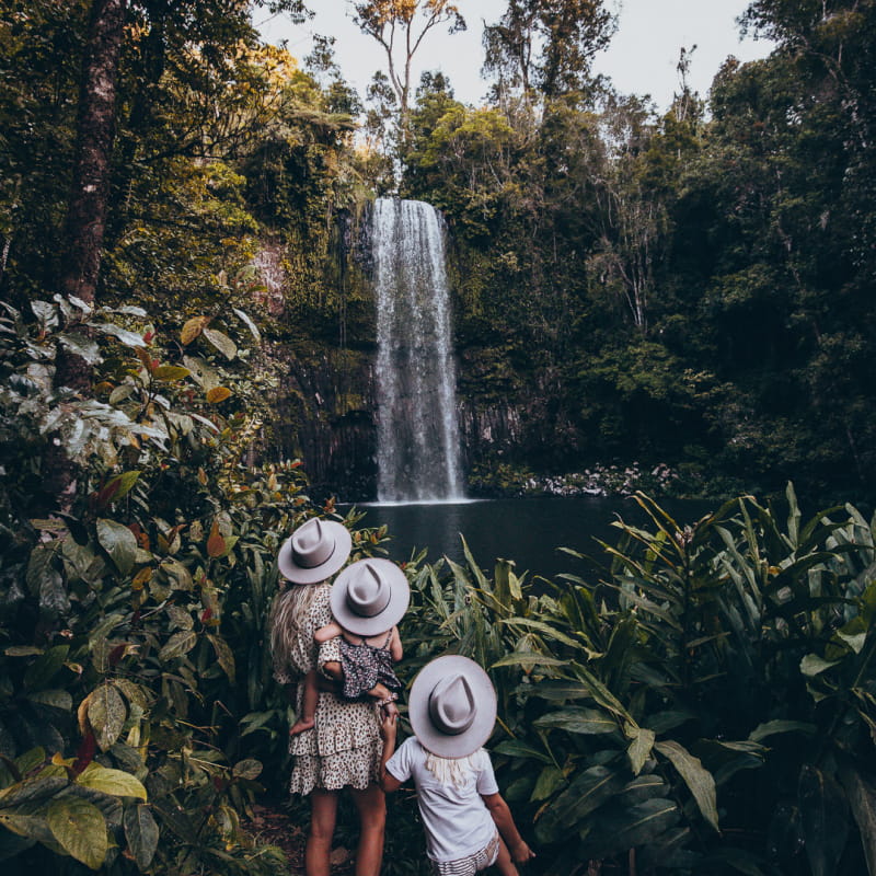 A woman and her two children are looking at a waterfall in front of them