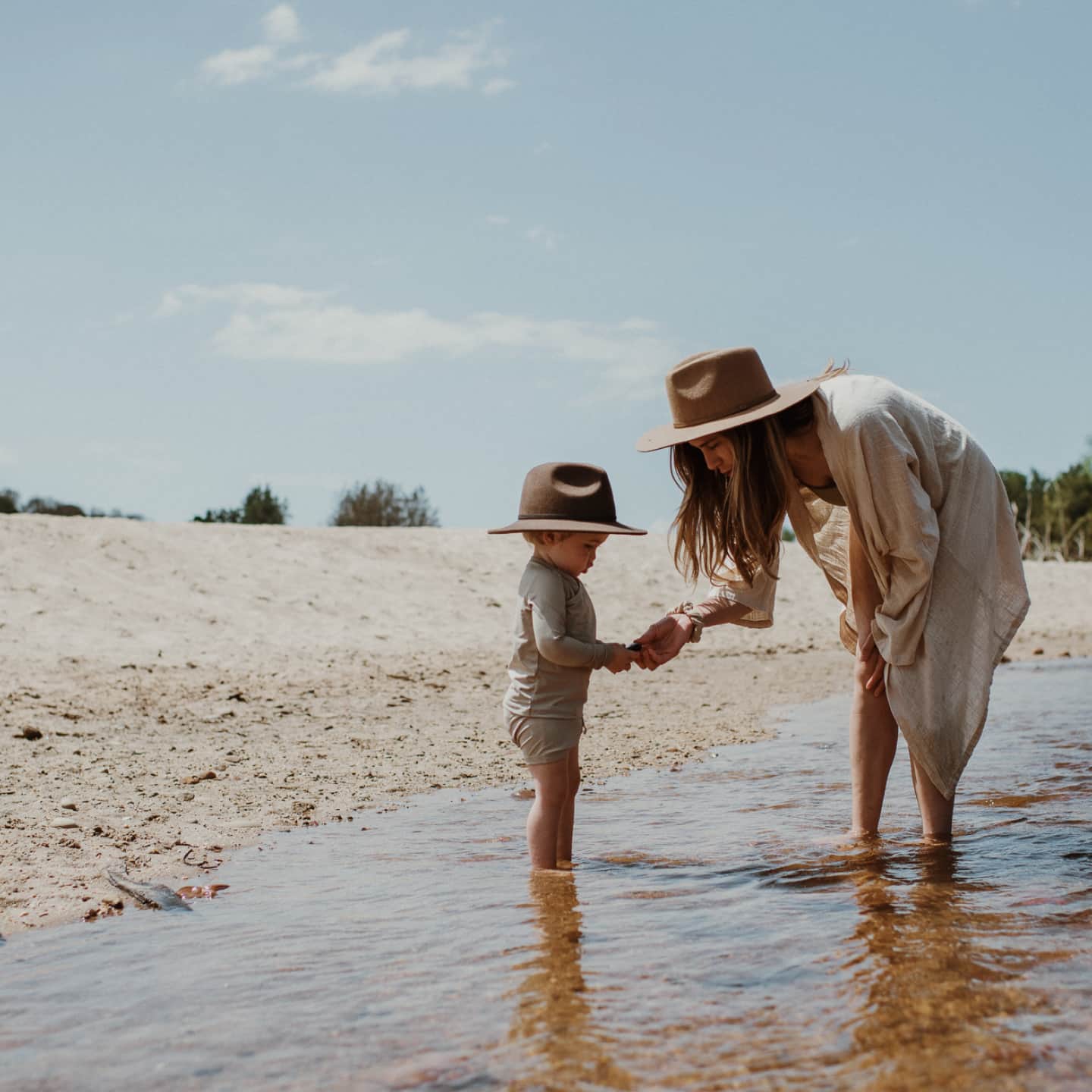 A woman and her son are standing in a creek bed holding a small stone