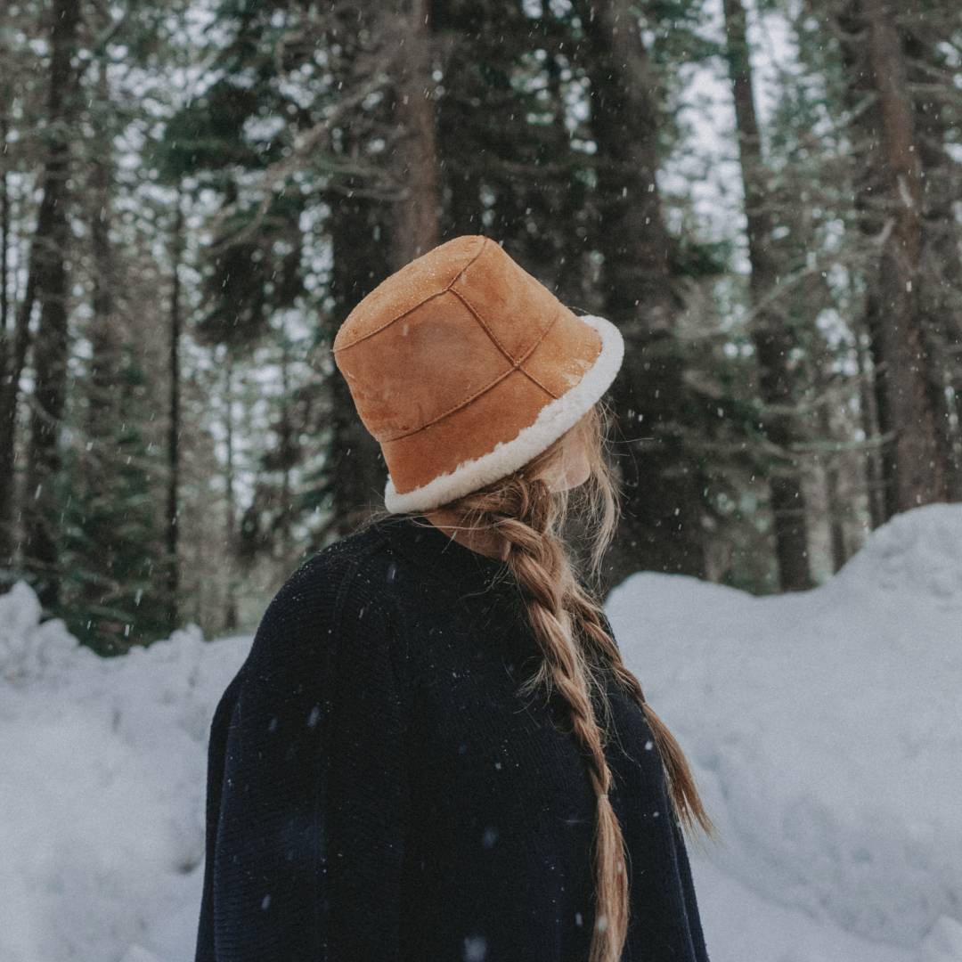 Woman with long hair wearing a sherpa bucket standing in the snow