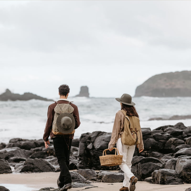 A man and a woman taking a picnic basket out onto the beach