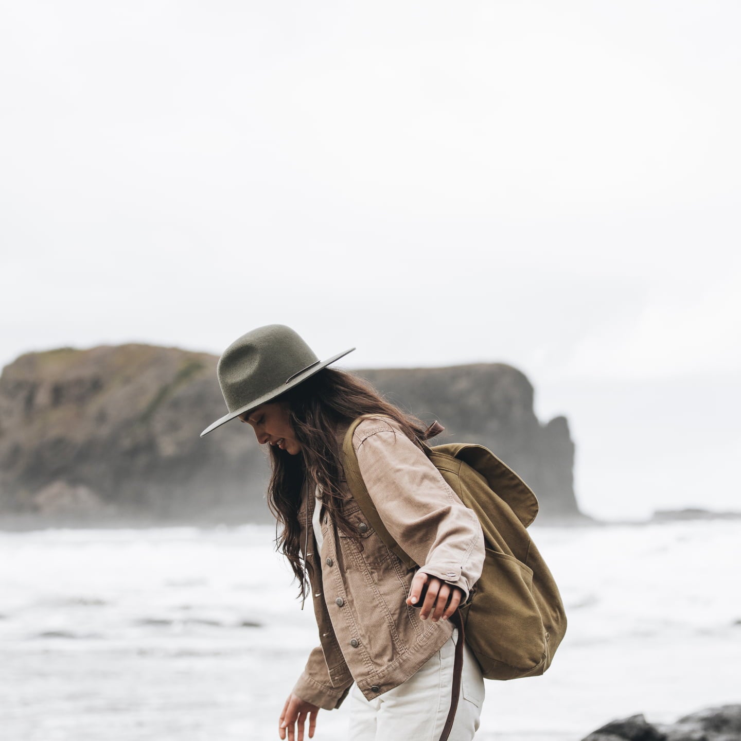 A girl with long hair wearing a wide brim hat walking outside