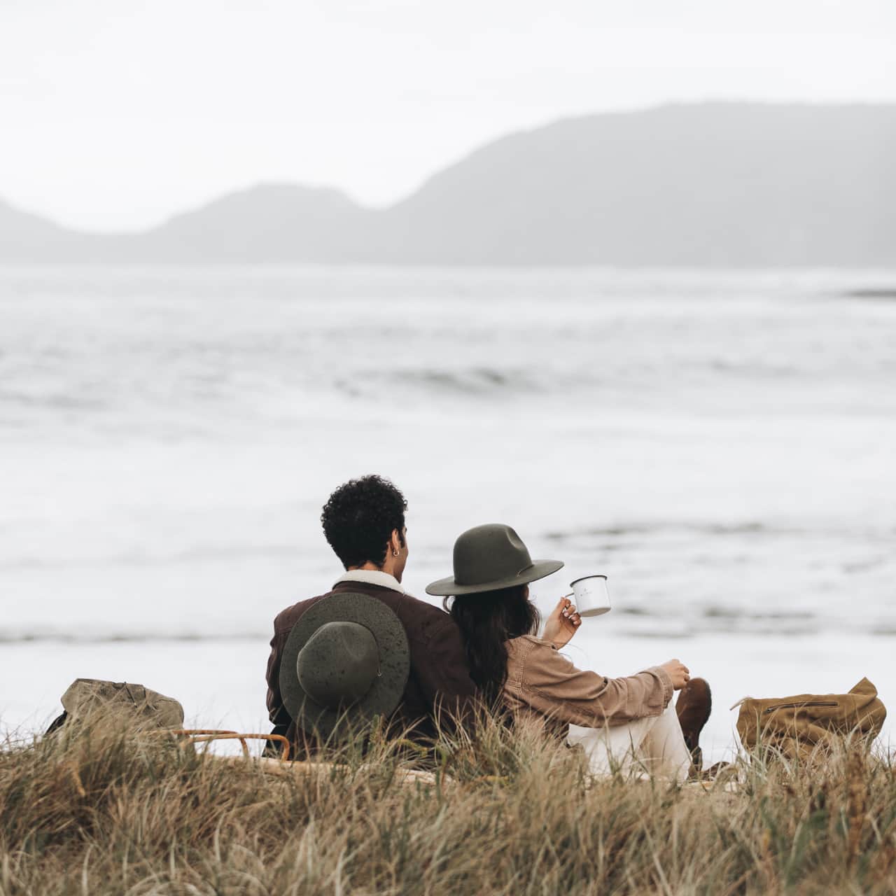 A man and a woman are having a picnic on top of a cliff overlooking the ocean